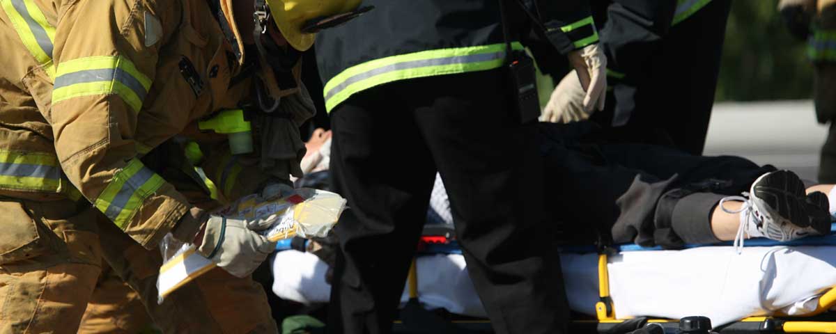 Firefighters leaning over a person who has been placed on a stretcher.